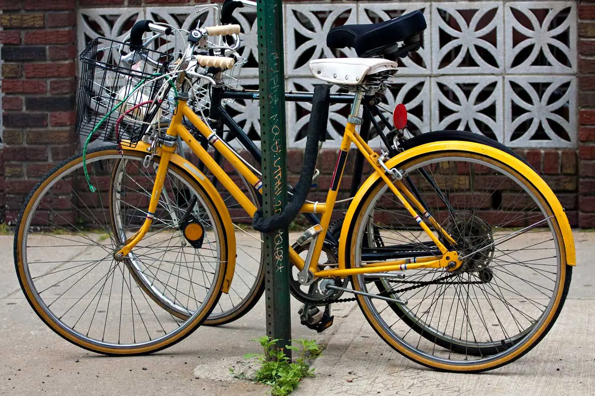 Deux vélos attachés à un poteau avec une chaîne antivol